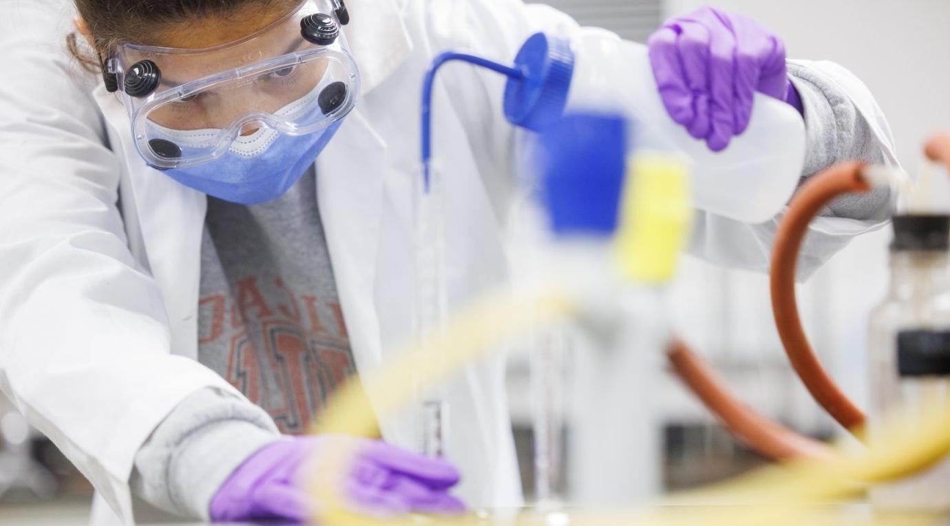 A Pitzer student washes a volumetric flask with solvent during a chemistry lab class