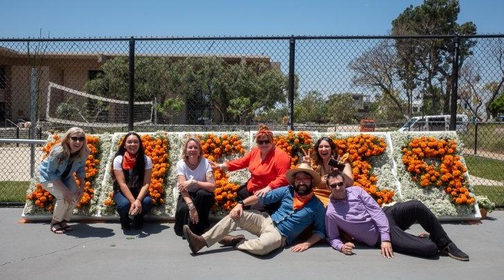 Registrar staff sitting in front of Pitzer flower sign