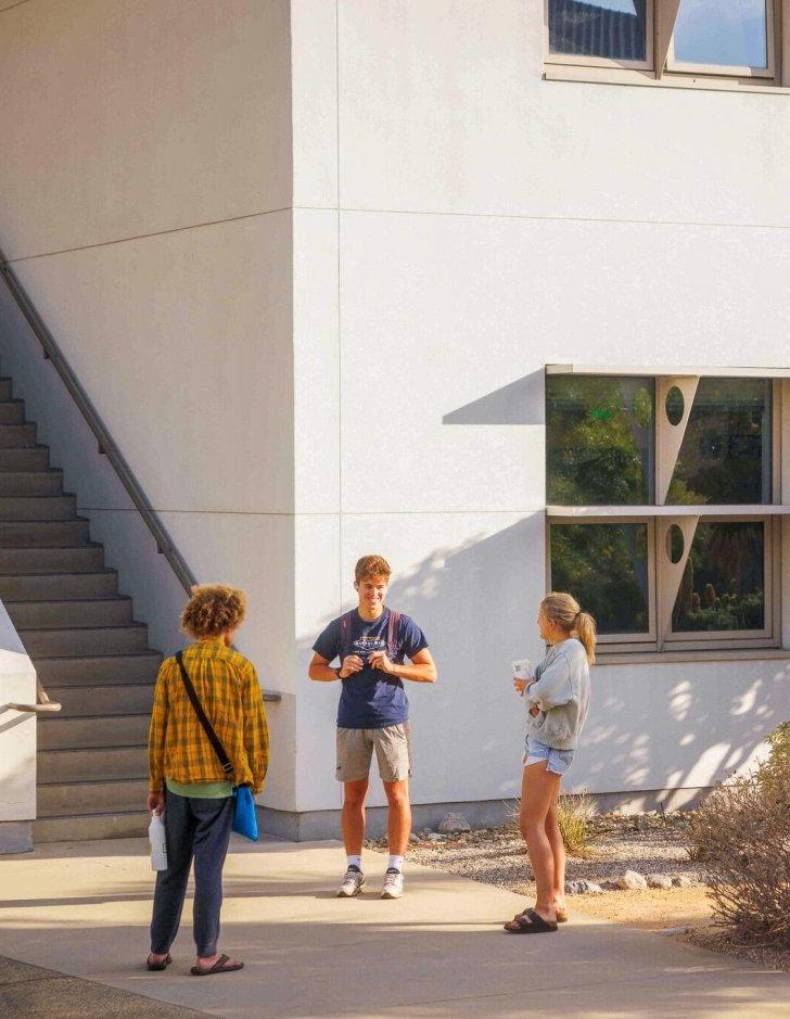 Three students talk in fron of Broad Hall external stairs