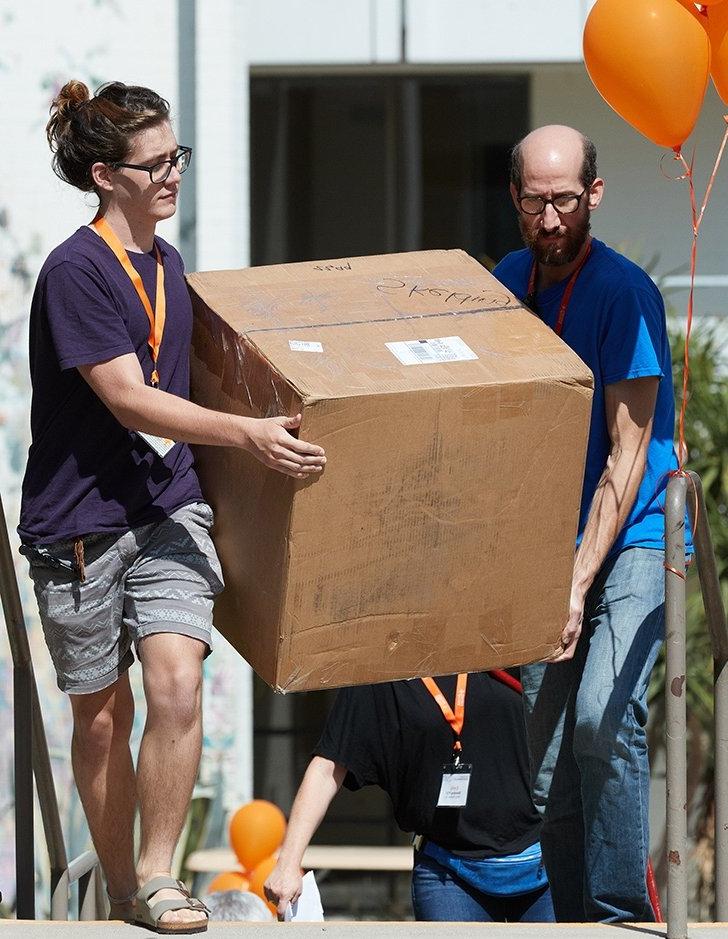 a parent and student carry a large box up stairs