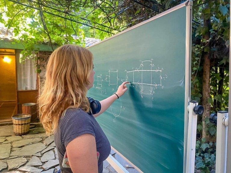 student solves math problem on an outdoor blackboard