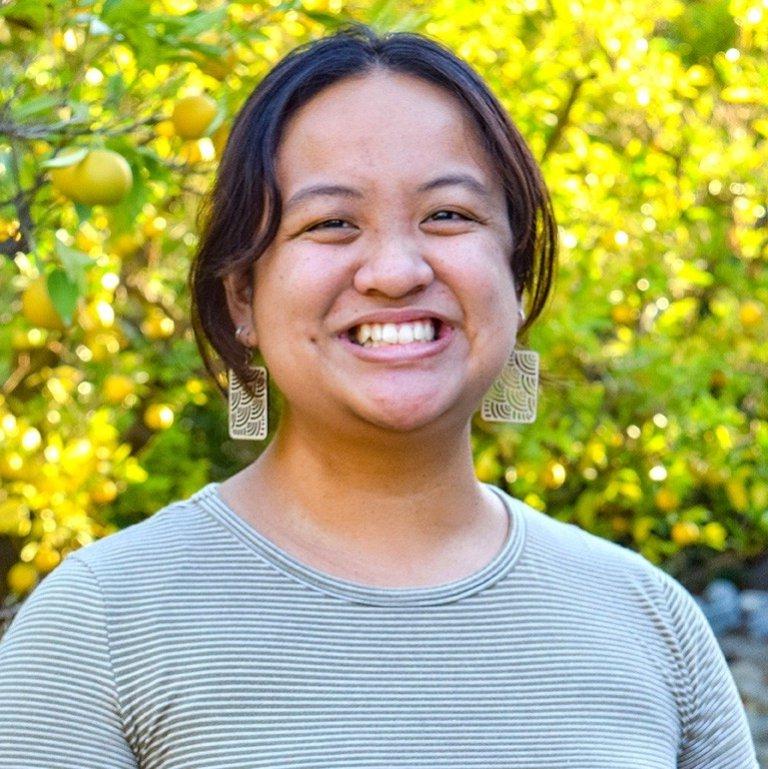 Malaya Caligtan Tran poses in front of Pitzer's orange groves